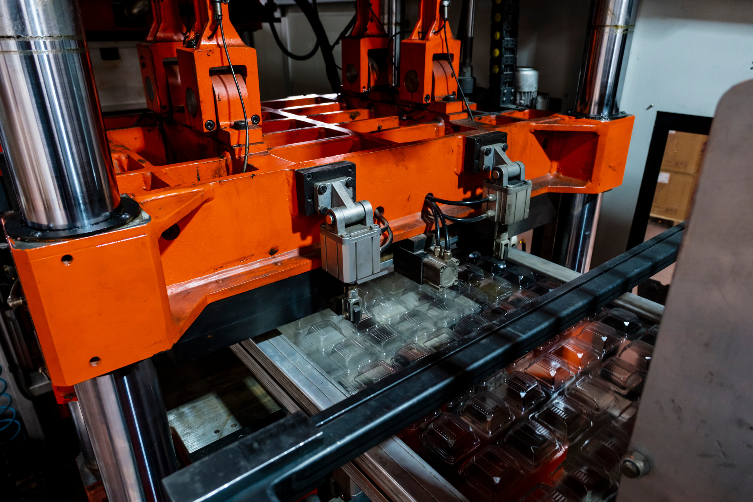 Vacuum thermoforming machine is used for producing plastic packaging in the factory. Close-up of the machine making a mold. Selective focus front